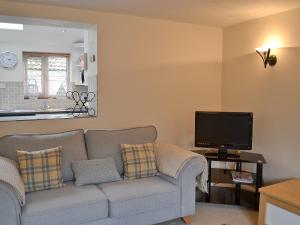 a living room with a couch and a tv at Pebble Cottage in Holt