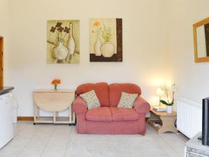 sala de estar con sofá rosa y pinturas en la pared en Little Wharf, en Loxton