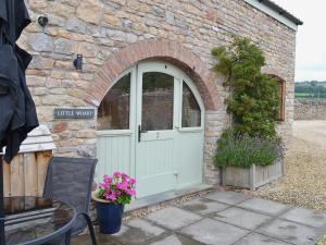 a stone building with an arched door and flowers at Little Wharf in Loxton