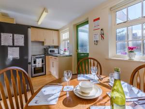een keuken en eetkamer met een tafel met een fles wijn bij Estate Cottage in Wheldrake