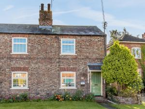 a brick house with a green door at Estate Cottage in Wheldrake