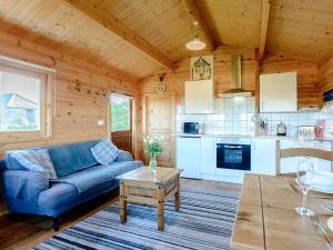 a living room with a blue couch and a kitchen at Buttercup Lodge in Broomhill
