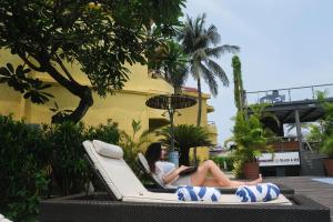 una mujer sentada en un sofá con un portátil en una piscina en Whispering Palms Beach Resort, en Candolim