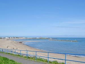 a beach with a blue fence next to the ocean w obiekcie Seashells w mieście Woodhorn