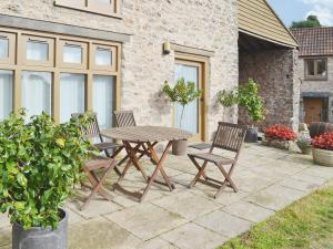 una mesa de madera y 2 sillas en el patio en The Threshing Barn en Westbury-sub-Mendip