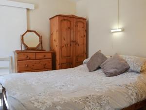 a bedroom with a bed with a dresser and a mirror at Bodwi Bach in Llanengan