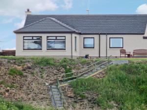 a house with a bench in front of it at The Waves in Wick