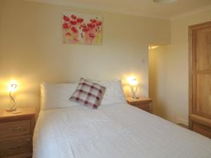 a bedroom with a white bed with two lamps on tables at The Waves in Wick
