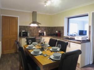 a dining room table with chairs and a kitchen at The Waves in Wick