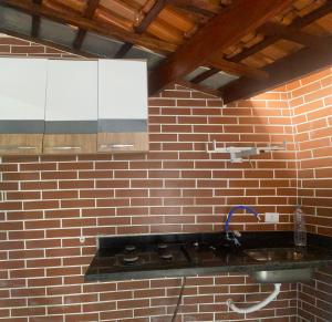 a bathroom with a sink and a brick wall at Colônia Virtual Net in Itanhaém