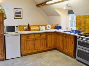 a kitchen with wooden cabinets and white appliances at Erw Goed Hen Stabl in Arthog