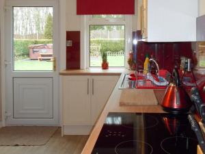 cocina con armarios blancos, fregadero y ventana en Blaeberry Cottage - 28061, en Dinwoodie Mains