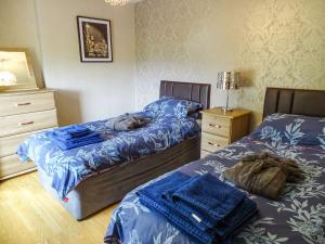 a bedroom with two beds and a cat sleeping on the bed at Blaeberry Cottage - 28061 in Dinwoodie Mains