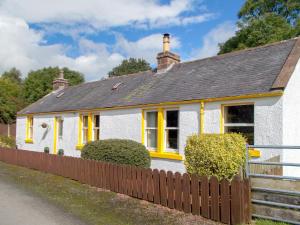 Casa blanca con ventanas amarillas y valla en Blaeberry Cottage - 28061, en Dinwoodie Mains