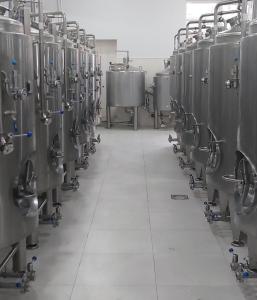 a row of silver tanks in a brewery at ARAGAST HOTEL & BREWERY пивоварня in Sevan