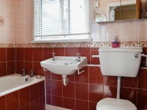 a bathroom with a sink and a toilet and a tub at Tan Y Fawnog in Penrhyndeudreath