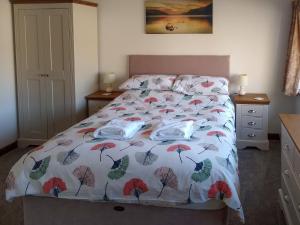 a bed with a comforter with leaves on it at Sparrow in Burton Bradstock