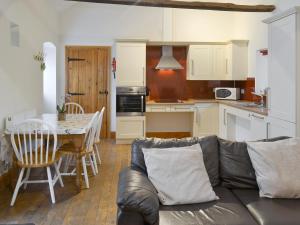 ein Wohnzimmer und eine Küche mit einem Sofa und einem Tisch in der Unterkunft The Old Dairy - 26726 in North Willingham