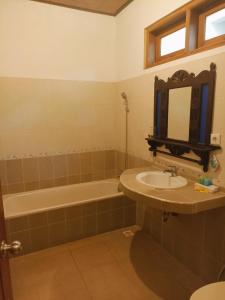 W łazience znajduje się umywalka, wanna i lustro. w obiekcie Kusnadi Hotel w mieście Legian