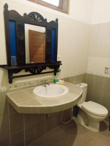 La salle de bains est pourvue d'un lavabo, de toilettes et d'un miroir. dans l'établissement Kusnadi Hotel, à Legian