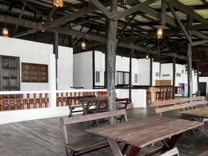 um quarto amplo com mesas e bancos de madeira em Lao Lake House em Vientiane