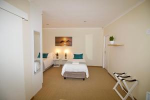 1 dormitorio con 2 camas y mesa con silla en Bush 2 Beach Inn en Summerstrand