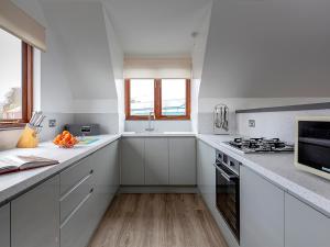a white kitchen with white cabinets and a stove top oven at Heron in Wroxham