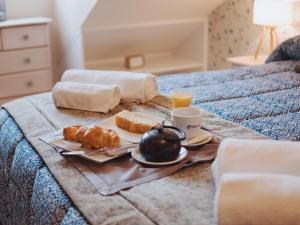 a breakfast tray with coffee and pastries on a bed at Apartamento "MACHOTE" in Tordesillas