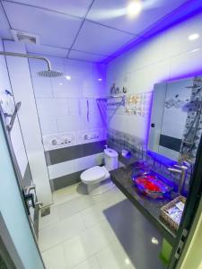 Tây Ninh的住宿－Khách sạn Vườn Cau & Khu vui chơi giải trí SaLa，浴室设有卫生间和带紫色照明的盥洗盆。