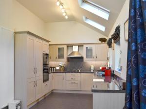 a kitchen with white cabinets and a skylight at Langside in Kingussie