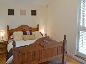 a bedroom with a wooden bed and two windows at The Hayloft in Stourport