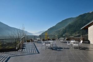 a patio with chairs and tables and mountains in the background at juSTa Grand View Resort & Spa, Manali in Manāli