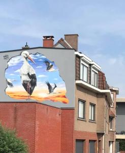 een groot billboard met een vogel aan de zijkant van een gebouw bij Gasthuis 20 verdiep 2 in Kuurne