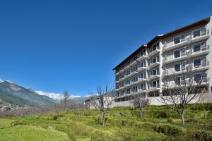 an apartment building with mountains in the background at juSTa Grand View Resort & Spa, Manali in Manāli