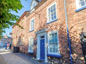 a brick building with a blue door on a street at Ellinor House in Cleobury Mortimer