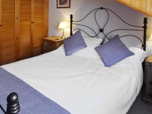ウィットビーにあるFriendship Cottageの白い大型ベッド(紫色の枕2つ付)