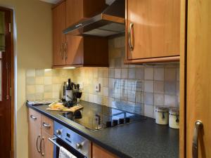 a kitchen with black counter tops and wooden cabinets at The Bothy in Glendevon