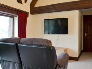 a living room with a couch and a flat screen tv at Church Farm Barn in Clippesby