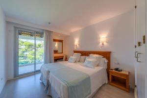 a bedroom with a bed and a large window at Playa Esperanza Resort Affiliated by Meliá in Playa de Muro