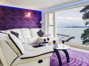 sala de estar con sofá blanco y pared morada en Riviera Mews, en Torquay