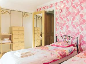 1 dormitorio con papel pintado de flores rosa y blanco en Riviera Mews, en Torquay