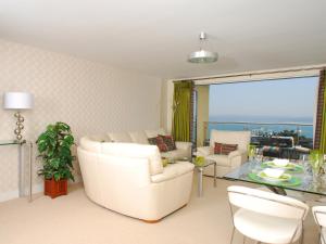 a living room with white furniture and a glass table at Tree Tops - A4 Masts in Torquay