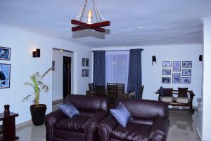 a living room with a leather couch and a ceiling fan at Enaiteru in Oyugis