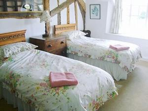 a bedroom with two beds with a pink pillow on them at Oddwell Cottage in Brompton Ralph