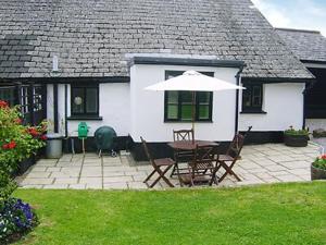 een patio met een tafel en stoelen en een parasol bij Oddwell Cottage in Brompton Ralph