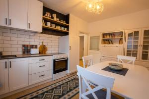 a kitchen with white cabinets and a table and chairs at City Block Apartment in Pristina +10 photos