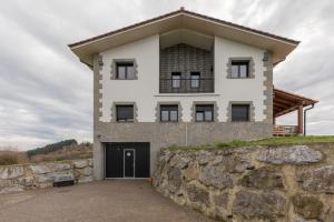 una gran casa blanca con un muro de piedra en Erretola - Baskey Rentals, en Aizarnazábal