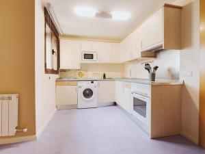 a kitchen with white cabinets and a washer and dryer at Apartamento SOFIA in Tordesillas