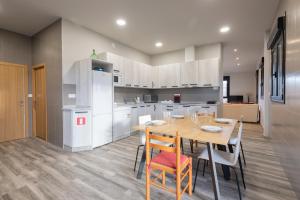 a kitchen with a wooden table and a kitchen with white cabinets at Erretola - Baskey Rentals in Aizarnazábal