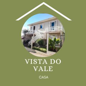 a vista do value logo com uma casa branca em Casa Vista do Vale próxima ao Vale dos Vinhedos em Bento Gonçalves